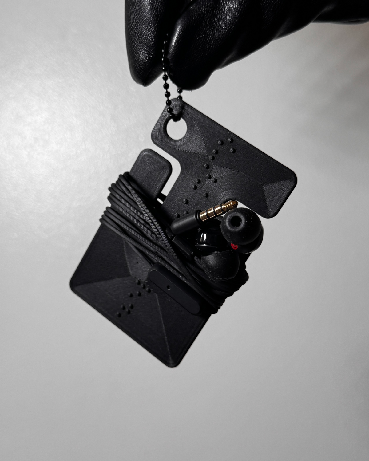 cable frame charcoal with wrapped earphones held by the ball chain